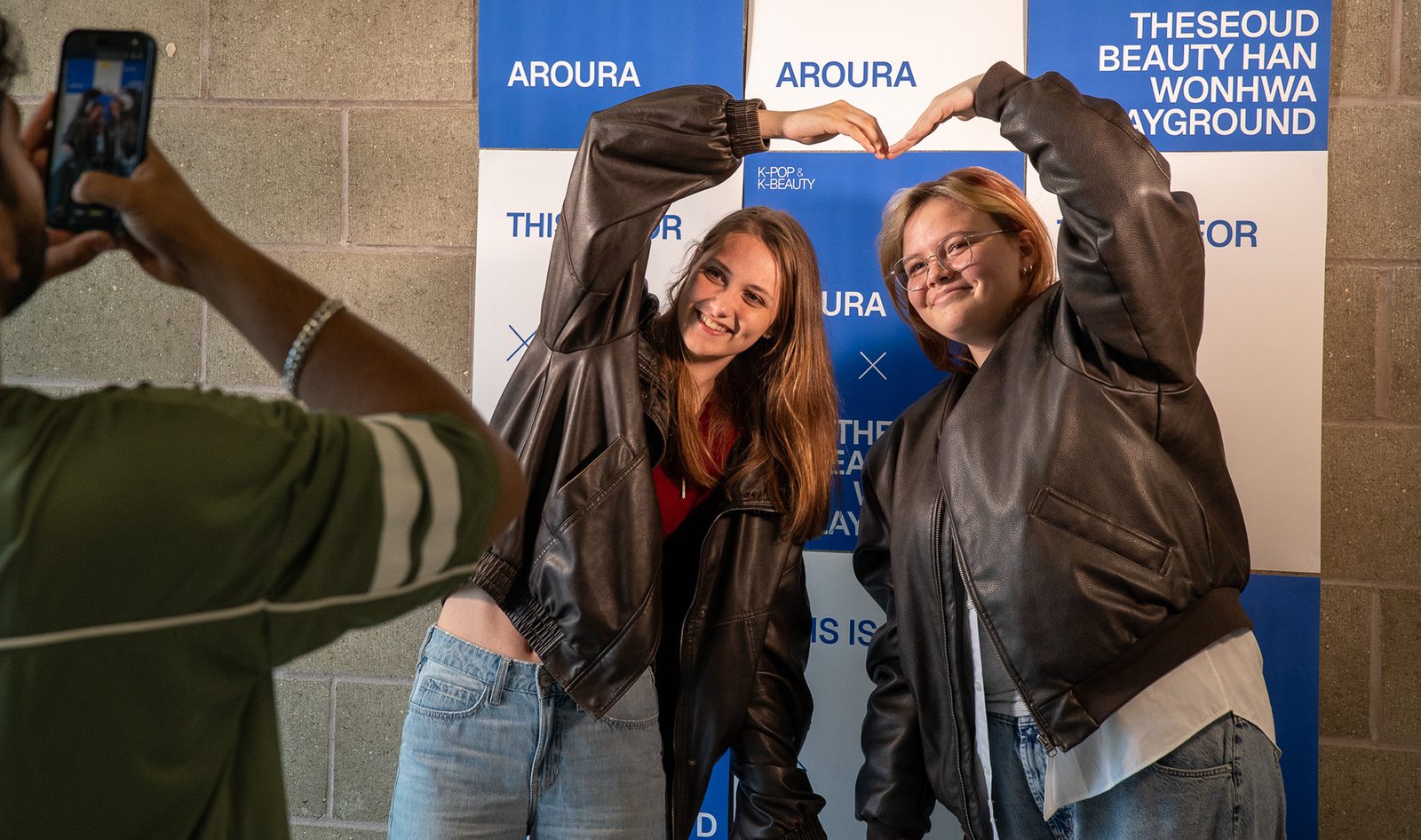 Two attendees posing in front of the Aroura AI backdrop.