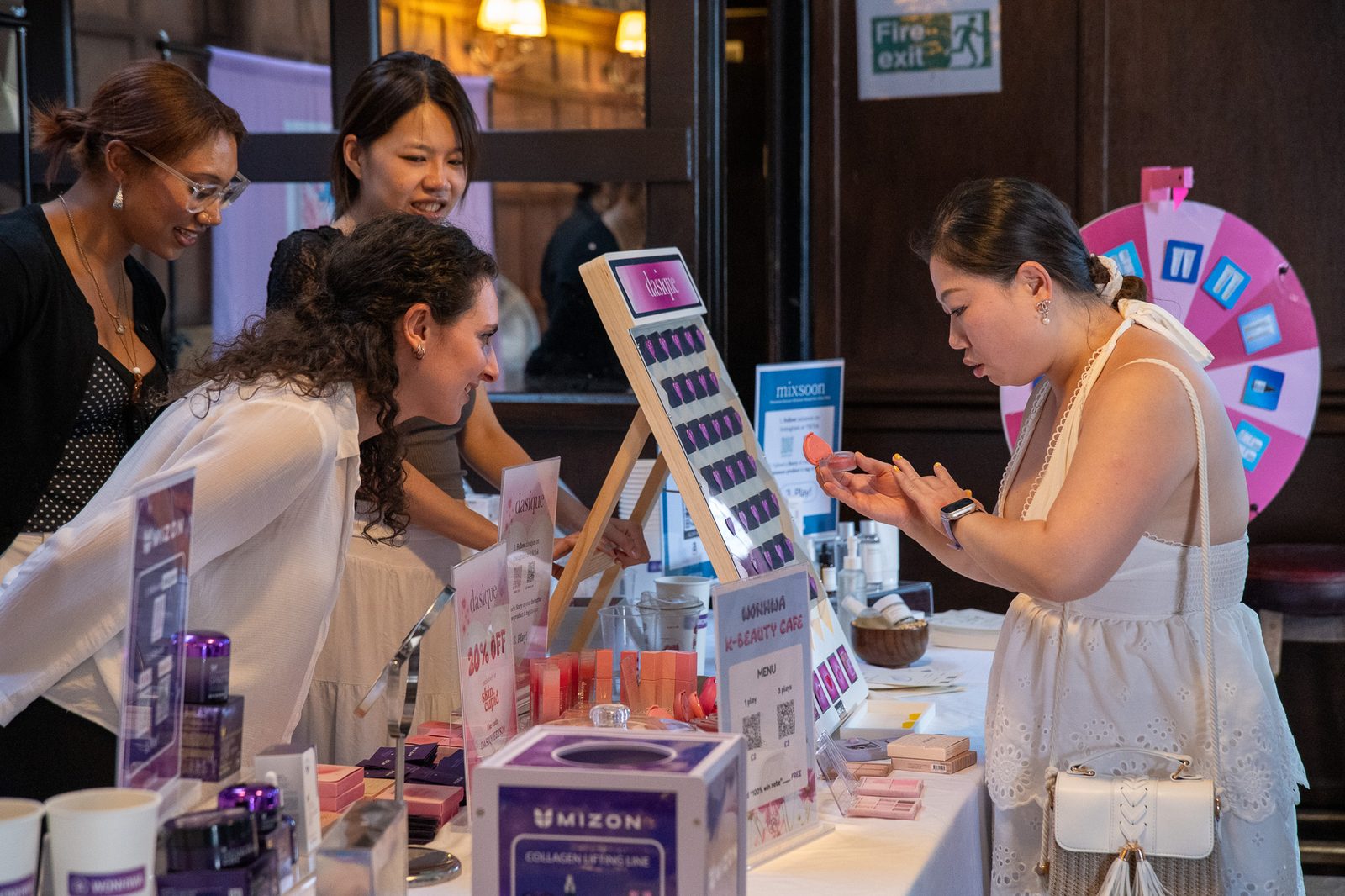 Visitors trying products at a brand table stocked with samples.
